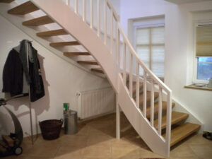 Das Foto zeigt eine Frei-Treppe mit weißem Geländer aus Holz. Geliefert und montiert von Stephan Johannßen.