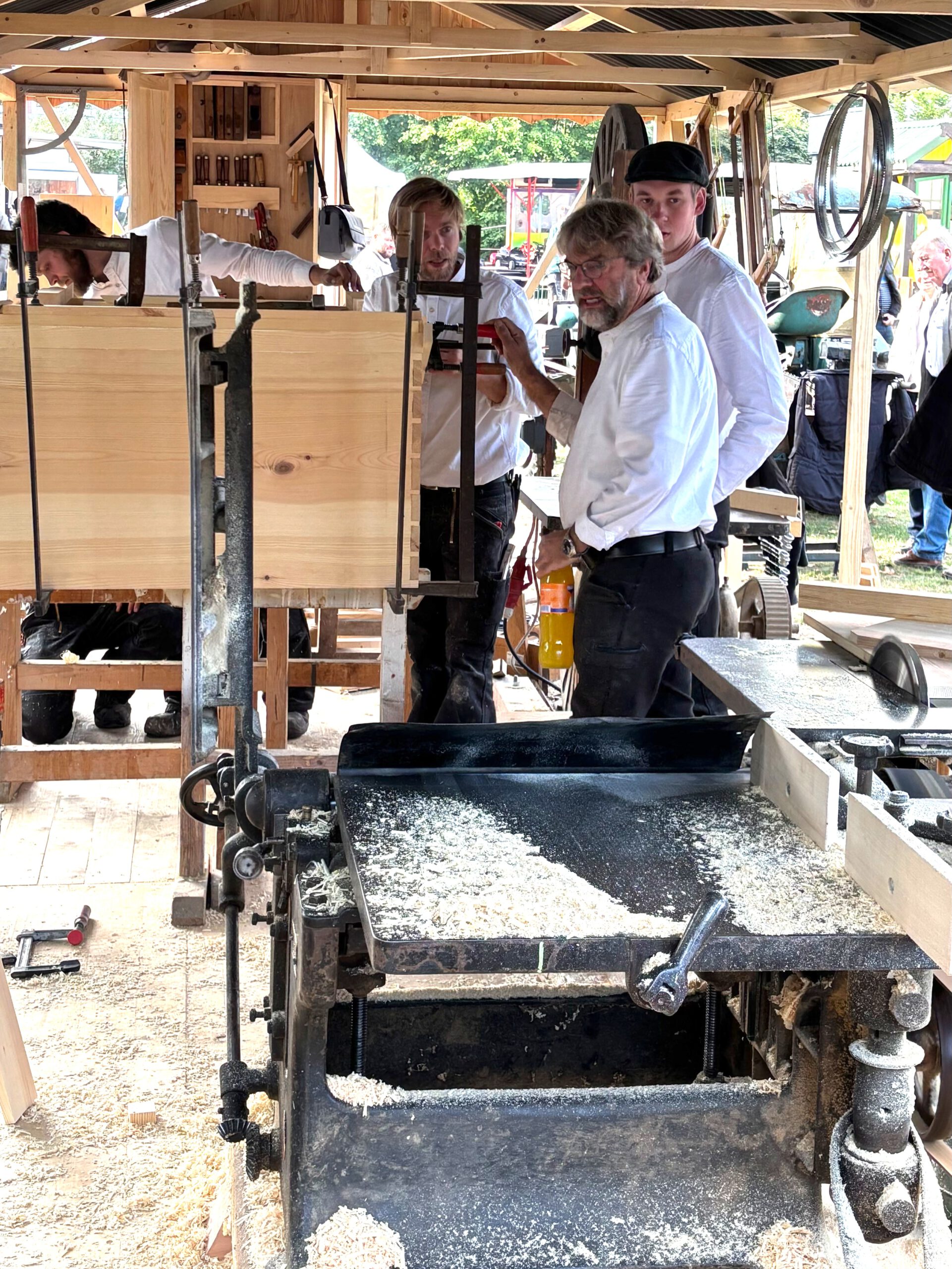 Das Foto zeigt diverse Kollegen der Tischlerei. Sie stehen hinter einer Hobelbank.