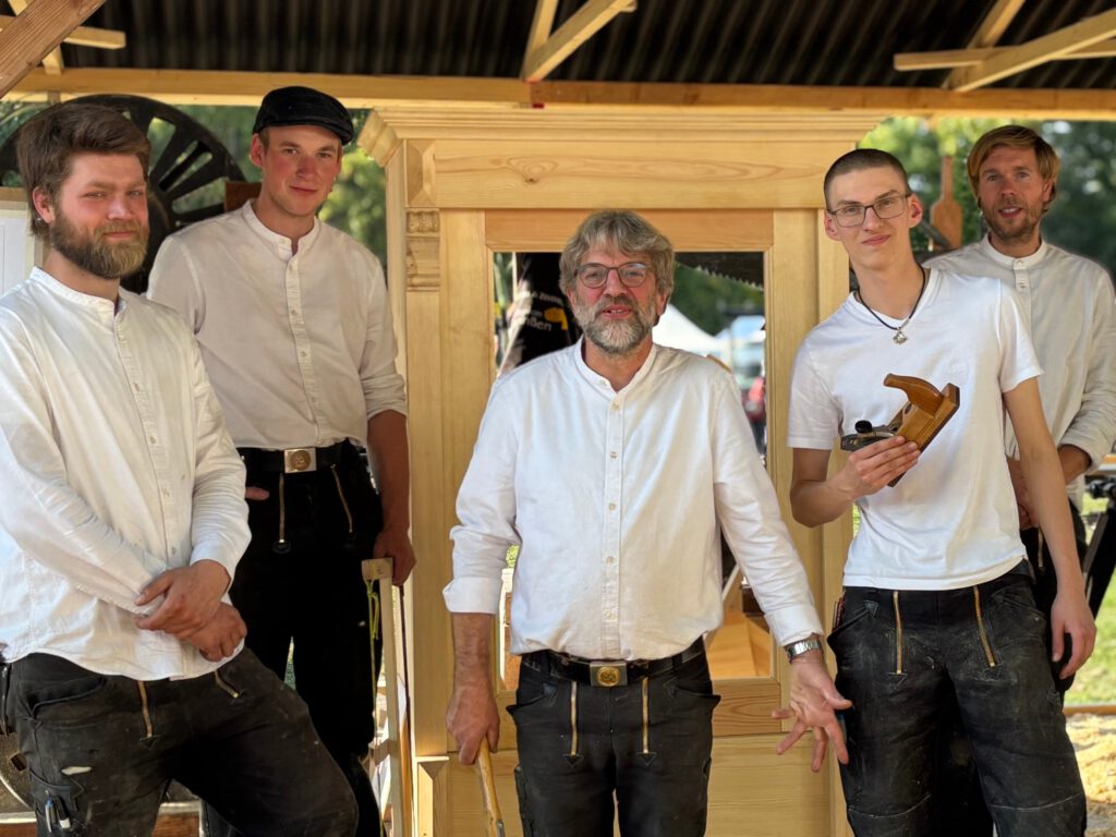 Das Foto zeigt das Team der Tischlerei und Zimmerei Stephan Johannßen. Zu sehen sind fünf Männer, die vor einem Werkstück stehen.